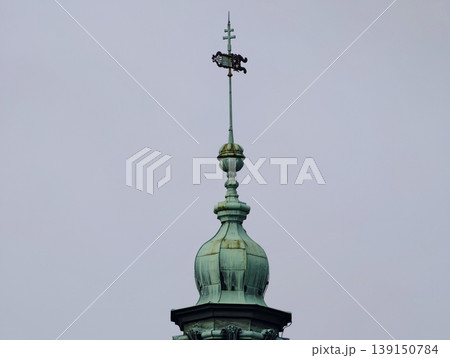 Copper finial with weather vane. Architectural feature with weather vane and decorative finial contrast 139150784