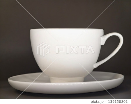 Refined white ceramic mug resting on saucer under vibrant studio lights highlighting sleek curves Refined white ceramic mug resting on saucer under vibrant studio lights highlighting sleek curves 139150801
