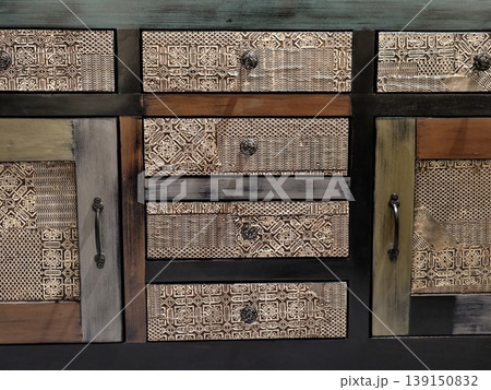 Decorative rustic storage unit featuring textured drawers and antique metal accents for warm interiors Decorative rustic storage unit featuring textured drawers and antique metal accents for warm interiors 139150832