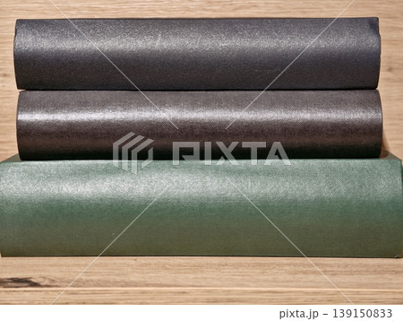 Multiple rolls of textured vinyl displayed on wooden surface suitable for renovation needs 139150833