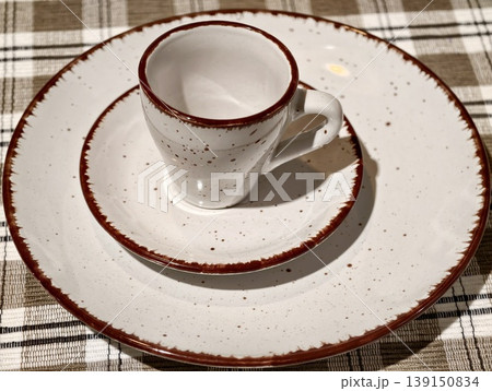 Vintage dishware on plaid table. Farmhouse table featuring speckled dishware and cozy rustic textures Vintage dishware on plaid table. Farmhouse table featuring speckled dishware and cozy rustic textures 139150834