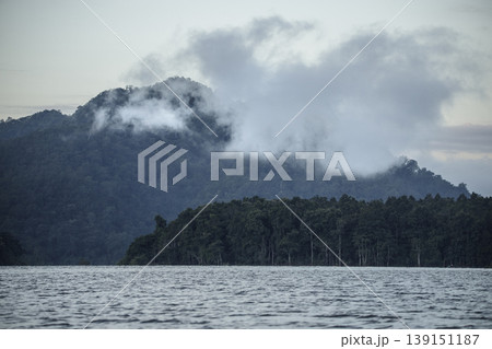 Serene landscape of mountains and a lake under early morning fog. 139151187