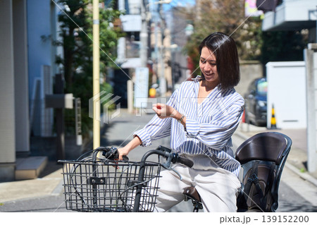 晴れた日に笑顔でママチャリを運転する日本人女性 晴れた日に笑顔でママチャリを運転する日本人女性 139152200