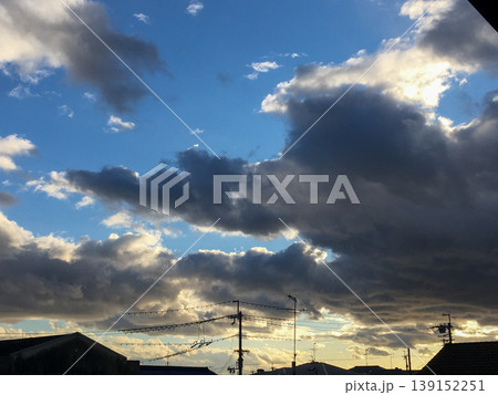 厚い雲の間から光が差し込む青空と街並みのシルエット 139152251