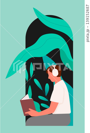 Man wearing noise canceling headphones reading book with plants 139152687