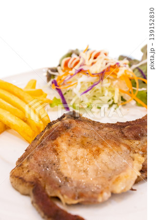 Top view of Steak pork chop with French Fries and Vegetable Salad put in the white dish, focus selective 139152830