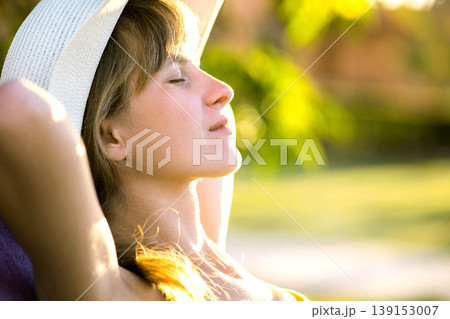 Young woman relaxing outdoors on sunny summer day. Happy lady lying down on comfortable beach chair daydreaming thinking. Calm beautiful smiling girl enjoying fresh air relaxing with closed eyes. Young woman relaxing outdoors on sunny summer day. Happy lady lying down on comfortable beach chair daydreaming thinking. Calm beautiful smiling girl enjoying fresh air relaxing with closed eyes. 139153007