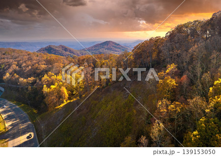 Winding parkway road in colorful mountain forest with yellow canopies in autumn at sunset. Driving in North Carolina wild woods nature in fall season 139153050