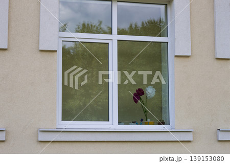View from outside of big window with bouquet of bright paper flowers and reflection of green trees. View from outside of big window with bouquet of bright paper flowers and reflection of green trees. 139153080