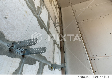 Unfinished brick wall in a room under construction prepared for drywall plates frame installation. 139153103