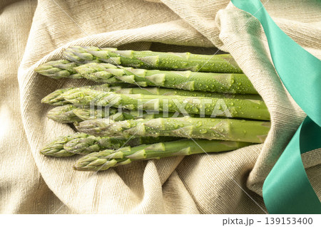 新鮮な緑のアスパラガスを並べた水滴輝く春野菜の写真 139153400