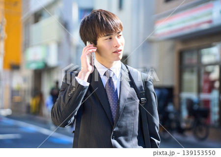 外回りの営業中に街中で電話対応をする若い日本人ビジネスマン 外回りの営業中に街中で電話対応をする若い日本人ビジネスマン 139153550