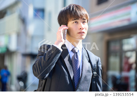 外回りの営業中に街中で電話対応をする若い日本人ビジネスマン 139153554