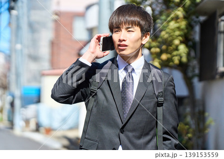 外回りの営業中に街中で電話対応をする若い日本人ビジネスマン 外回りの営業中に街中で電話対応をする若い日本人ビジネスマン 139153559