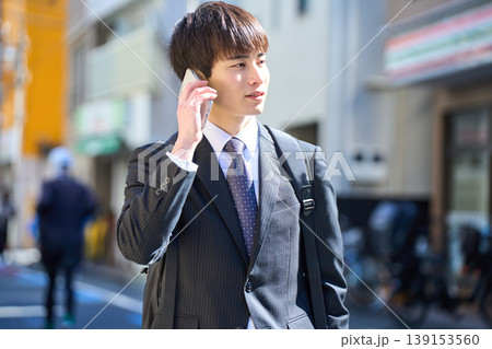 外回りの営業中に街中で電話対応をする若い日本人ビジネスマン 外回りの営業中に街中で電話対応をする若い日本人ビジネスマン 139153560