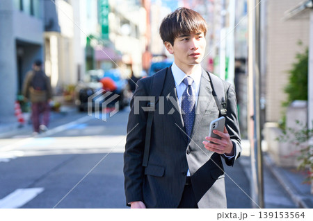 外回りの営業中に街中で電話対応をする若い日本人ビジネスマン 外回りの営業中に街中で電話対応をする若い日本人ビジネスマン 139153564
