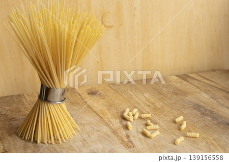Bundle of dry spaghetti and fusilli pasta on wooden background Bundle of dry spaghetti and fusilli pasta on wooden background 139156558