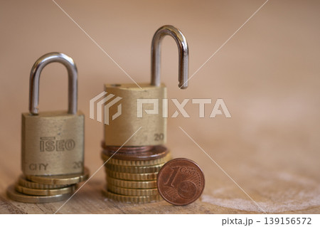 TITLE: Unlocked Brass Padlock on Euro Coins Showing Financial Vulnerability 139156572