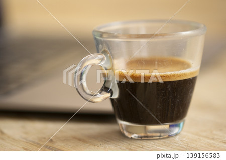Close up of glass espresso cup with golden crema on wooden table 139156583