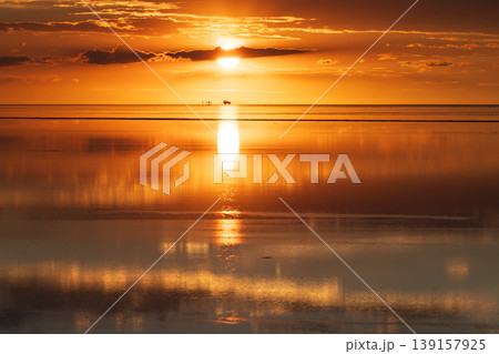 Peaceful sunset reflection over vast salt flat in uyuni bolivia Peaceful sunset reflection over vast salt flat in uyuni bolivia 139157925