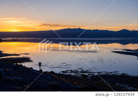 Peaceful sunset sky reflection on calm lake with mountain silhouette Peaceful sunset sky reflection on calm lake with mountain silhouette 139157939