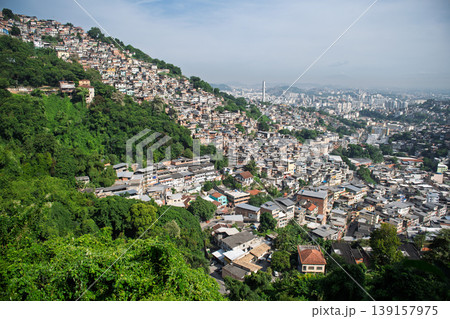 Vibrant cityscape of rio de janeiro displaying dense favela on lush green mountain slope overlooking urban skyline Vibrant cityscape of rio de janeiro displaying dense favela on lush green mountain slope overlooking urban skyline 139157975