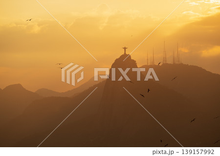 Serene golden sunset silhouette of Christ Redeemer on Corcovado mountain famous landmark in Rio de Janeiro Brazil 139157992