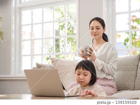 リビングでノートパソコンを使う子供と見守る母親 リビングでノートパソコンを使う子供と見守る母親 139159320