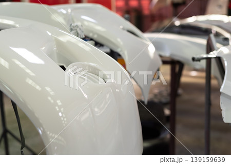 Close up of white car body panels in workshop after paint process glossy finish automotive repair and manufacturing quality control and restoration environment Close up of white car body panels in workshop after paint process glossy finish automotive repair and manufacturing quality control and restoration environment 139159639