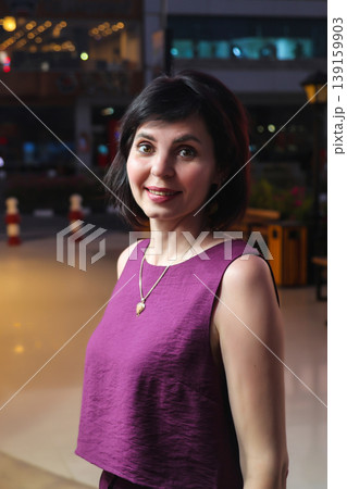 An adult woman near a store window late in the evening 139159903