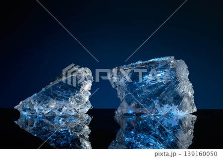 Broken ice with blue backlight on a black reflective background. 139160050