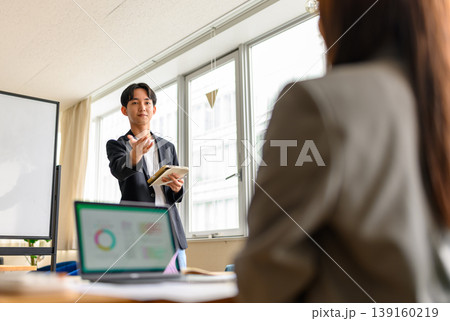 オフィスでホワイトボードを指しながら解説する講師(男性) オフィスでホワイトボードを指しながら解説する講師(男性) 139160219