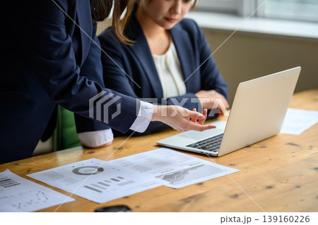 資料を見ながらノートパソコンを確認するビジネスパーソン 資料を見ながらノートパソコンを確認するビジネスパーソン 139160226