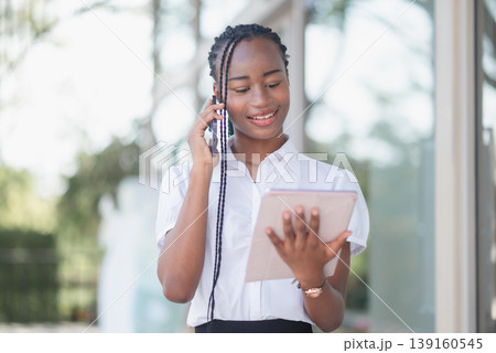 Young Black business woman checking smartphone while holding paper receipt outdoors. Mobile payment review, expense tracking, budget control, digital banking and personal finance concept. 139160545
