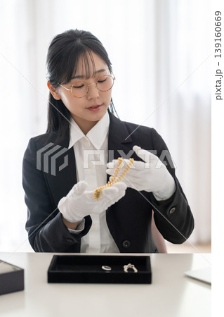貴金属を丁寧に査定する買取専門店の女性スタッフ 139160669
