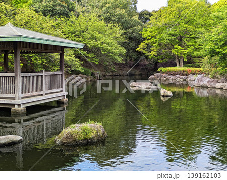日本庭園風の東屋と苔むした石が浮かぶ静かな池　新緑の木々　春 139162103