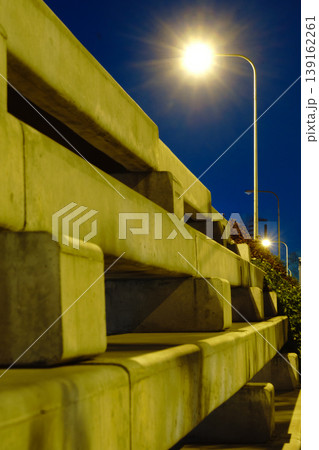Night scene of a modern bridge with illuminated streetlights and a city skyline in the background 139162261