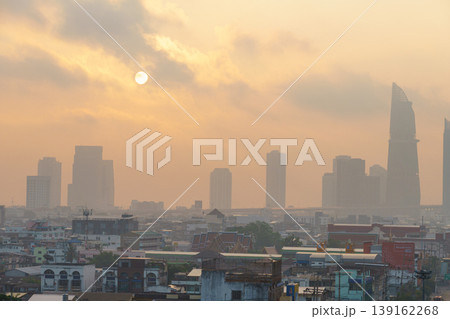 Sunset over a busy city skyline shrouded in haze with tall skyscrapers silhouetted against a warm, glowing sky, urban sunset scene with fuzzy atmosphere Sunset over a busy city skyline shrouded in haze with tall skyscrapers silhouetted against a warm, glowing sky, urban sunset scene with fuzzy atmosphere 139162268