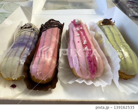 Multicolored glazed eclairs in a pastry box, French dessert and sweet pastry close-up Multicolored glazed eclairs in a pastry box, French dessert and sweet pastry close-up 139162535
