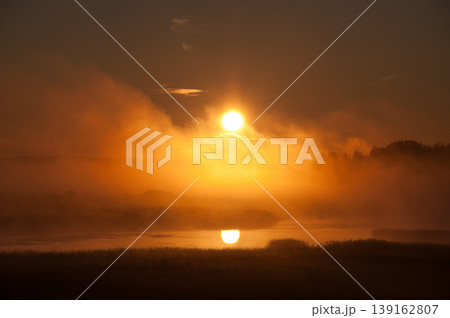 Rising sun behind the early morning fog in the Kokemaenjoki river delta in Pori, Finland Rising sun behind the early morning fog in the Kokemaenjoki river delta in Pori, Finland 139162807