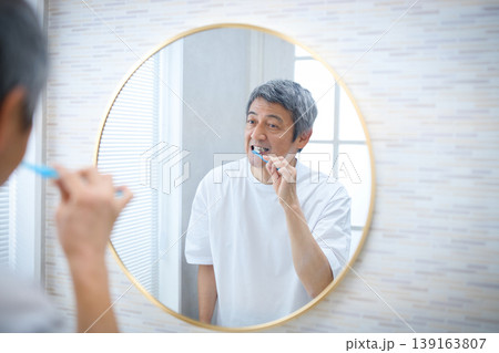 鏡を見ながら歯磨きをする60代の男性 鏡を見ながら歯磨きをする60代の男性 139163807