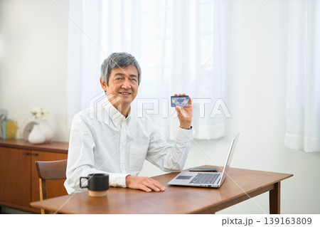 リビングでパソコンとカードを見る60代の男性 リビングでパソコンとカードを見る60代の男性 139163809