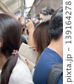 Candid picture of woman reading the book inside the subway train among the crowded passengers during rush hours in the city 139164278
