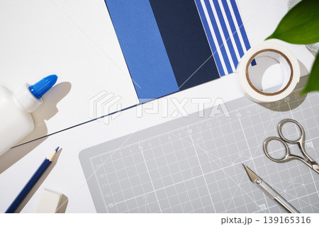 Top view of crafting tools on a grey cutting mat with blue paper samples. Copyspace 139165316