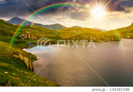 sunset over lovely summer scenery of alpine capra lake with steep slopes. nice view of transylvania alps, sibiu county. southern carpathian mountains of romania travel background with rainbow sunset over lovely summer scenery of alpine capra lake with steep slopes. nice view of transylvania alps, sibiu county. southern carpathian mountains of romania travel background with rainbow 139165396