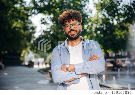 Arms crossed, standing. Handsome man is outdoors in the city Arms crossed, standing. Handsome man is outdoors in the city 139165856