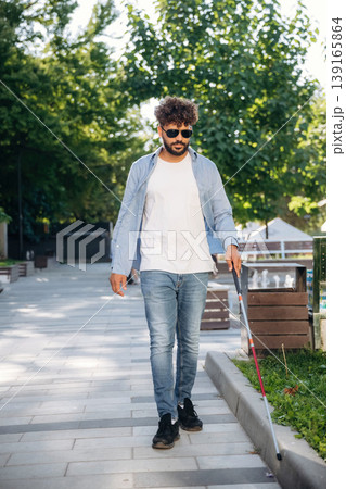Having a walk, using cane stick. Blind man with white cane and sunglasses is in the city Having a walk, using cane stick. Blind man with white cane and sunglasses is in the city 139165864