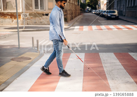 Crossing the road. Blind man with white cane and sunglasses is in the city Crossing the road. Blind man with white cane and sunglasses is in the city 139165888