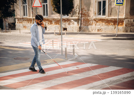 Crossing the road. Blind man with white cane and sunglasses is in the city Crossing the road. Blind man with white cane and sunglasses is in the city 139165890