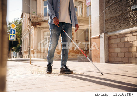 Walking on the pavement. A blind man with white cane is in the city Walking on the pavement. A blind man with white cane is in the city 139165897